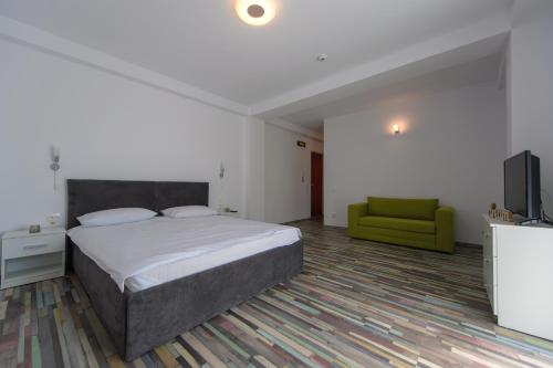 a bedroom with a bed and a green chair at Los Anghelos in Vama Veche