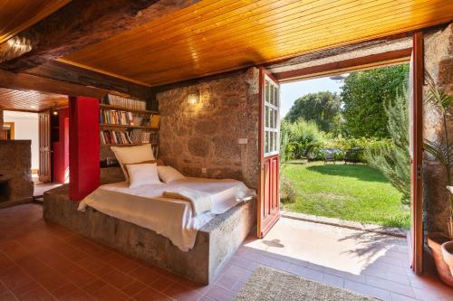 een slaapkamer met een bed en een groot raam bij Casa do Eido - sustainable living & nature experiences Gerês in Geres