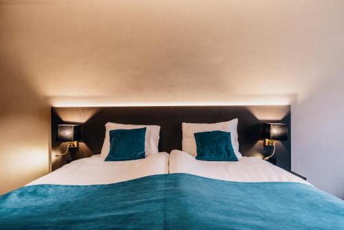 a bedroom with two beds with blue pillows at Hotel Hoogeveen in Hoogeveen