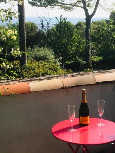 a red table with two glasses and a bottle of wine at T2 de la Bastide Rouge vue exceptionnelle (180°) sur Aix domaine privé T2 indépendant de 37 m2 avec terrasse exposée plein sud Piscine 10 X 5 in Aix-en-Provence