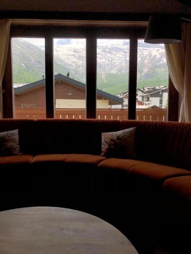 a couch in a living room with a large window at Blomatu II Top Floor in Saas-Fee