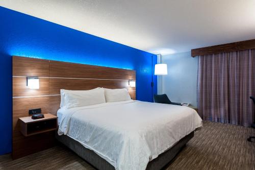 a hotel room with a large bed and a blue wall at Holiday Inn Express Cape Coral-Fort Myers Area by IHG in Cape Coral