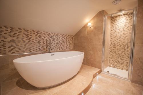 a bathroom with a large white tub and a shower at High Oaks Grange - Cottages in Pickering