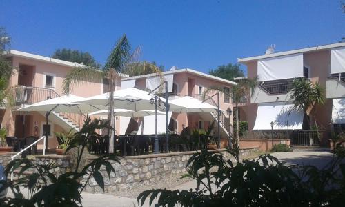 ein rosafarbenes Gebäude mit weißen Sonnenschirmen davor in der Unterkunft Hotel San Domenico in Marina di Camerota