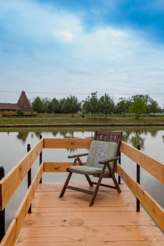 a chair sitting on a wooden dock next to a body of water at Tatarska Zagroda - Agroturystyka Dolina Baryczy Noclegi - Domek Jelonek in Krośnice