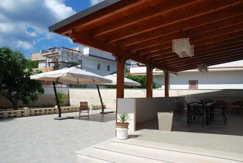 a patio with an umbrella and tables and chairs at Villa Cohiba - 700m dal mare in Pulsano