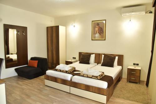 Habitación de hotel con cama y silla en Apartmani Centar Kumanovo, en Kumanovo