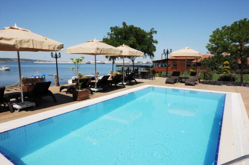 a swimming pool with chairs and umbrellas at Phellos Suites Boutique Hotel in Şile