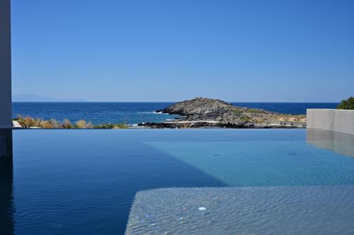 a pool of water with a view of the ocean at Kavos Hotel & Suites in Stavros