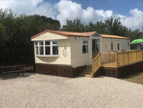 a small white house with a porch and a bench at Countryside views from a luxury mobile home near Perranporth in Perranporth