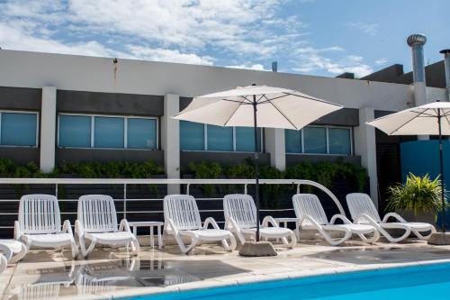 a group of white chairs and umbrellas next to a pool at Maran Suites & Towers in Paraná