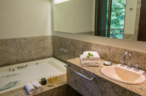 a bathroom with a sink and a bath tub at Garden Hill Hotel e Golfe in São João del Rei