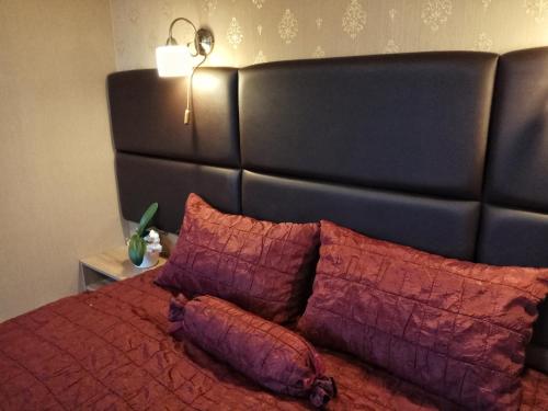 a bed with a black headboard with red sheets and pillows at Károlyi Panzió in Eger