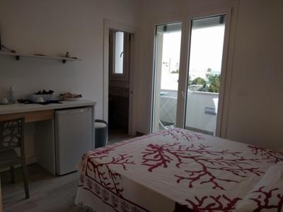 a bedroom with a bed and a desk and a window at La Bussola in Porto Cesareo