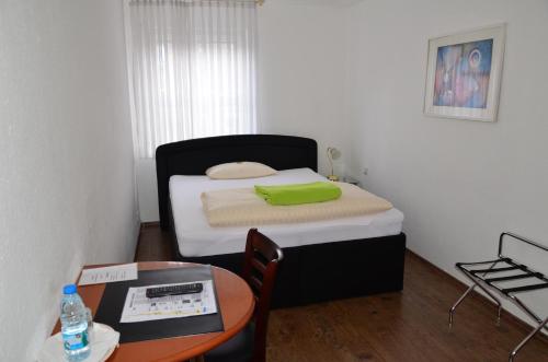 a small bedroom with a bed and a table at Hotel Mörike in Ludwigsburg