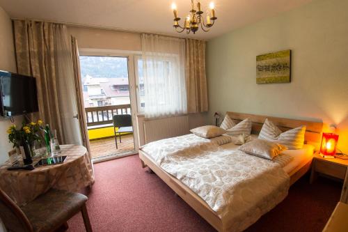 a bedroom with a large bed and a balcony at Europa Pension Tirol in Fliess