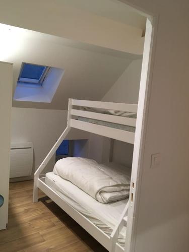 Ce lit superposé blanc se trouve dans un dortoir doté d'une fenêtre. dans l'établissement Gite Bord de Mer 80 m2, à Bernières-sur-Mer