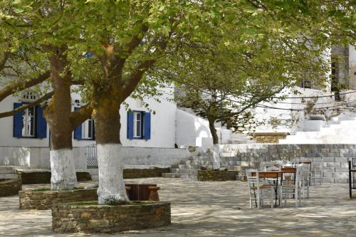 two trees with chairs and tables in front of a building at Aegean Breeze in DYO CHORIA TINOS in Triandáros