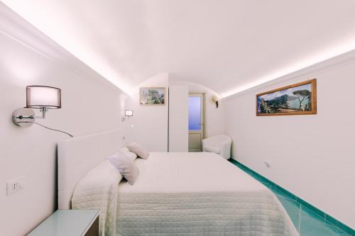 a white bedroom with a bed and a lamp at B&B IL CORTILE in Ravello