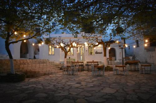 a patio with tables and chairs in front of a building with lights at Aegean Breeze in DYO CHORIA TINOS in Triandáros