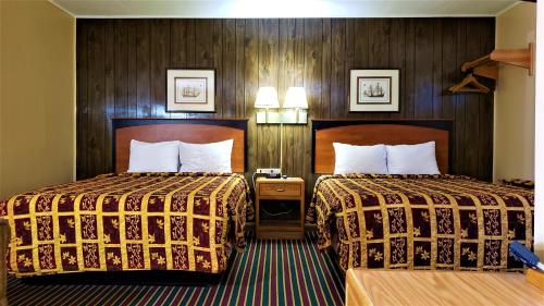 two beds in a hotel room with wooden walls at Grand Motel in Hastings