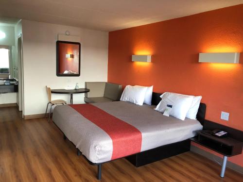 a bedroom with a large bed with an orange wall at Motel 6-Brunswick, GA in Brunswick