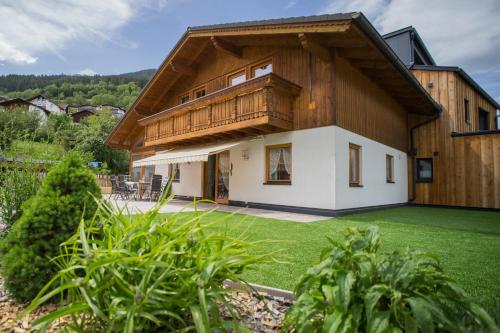 a house with a wooden roof and a green yard at Alpenzeit in Ladis