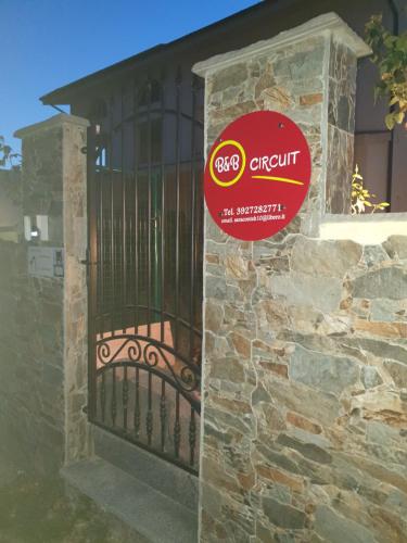 a gate in a stone wall with a sign on it at B&B Circuit in Borgo San Lorenzo