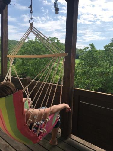 a woman laying in a hammock on a porch at Zur Glashütte Landpension in Fabrikschleichach
