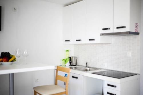 a kitchen with white cabinets and a sink and a chair at Apartments ANA Karlobag in Karlobag