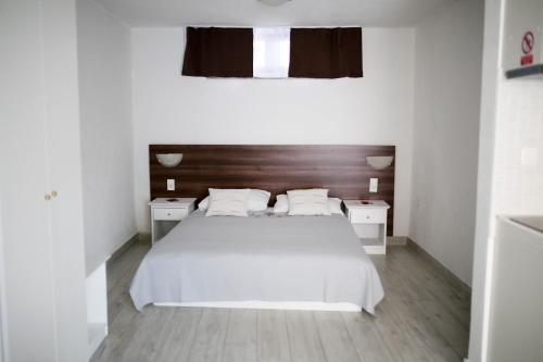 a white bedroom with a white bed and two night stands at Apartments ANA Karlobag in Karlobag