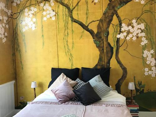 a bedroom with a tree mural behind a bed at B&B Valkenbos in The Hague