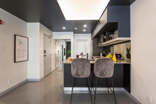 una cucina con due sgabelli da bar a bancone di Pierce Boutique Apartments by Simplissimmo a Montréal