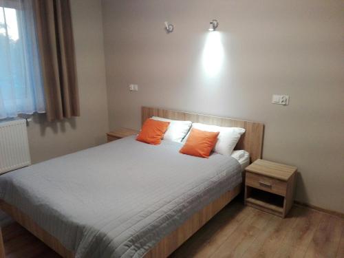 a bedroom with a bed with two orange pillows at Apartamet Marzenie 7 - Opole in Opole