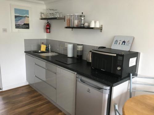 a kitchen with a black counter top with a microwave at Kiki’s Corner in Newquay