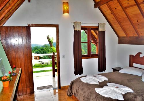 a bedroom with a bed and a large window at Chalés Fazenda Vale da Mata in Monte Verde