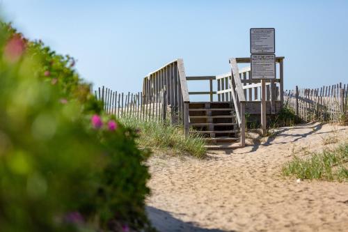 a bench on the beach next to a fence at The Ocean Resort Inn in Montauk