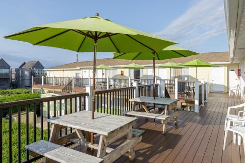 a deck with two picnic tables and an umbrella at The Ocean Resort Inn in Montauk