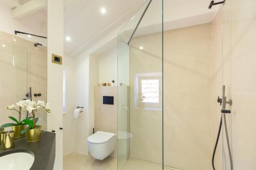 a bathroom with a shower and a toilet and a sink at Old Town House with Floor Heating & Lush Private Garden in Dubrovnik