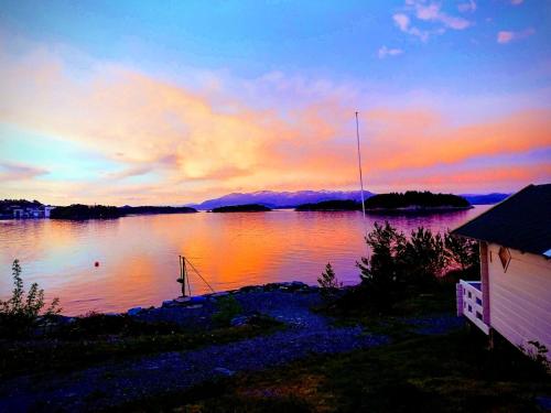 a sunset over a body of water with a house at Sponavik Camping in Stord