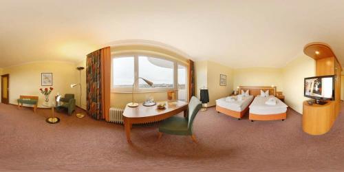 a hotel room with two beds and a table and a television at Ringhotel Parkhotel Witten in Witten