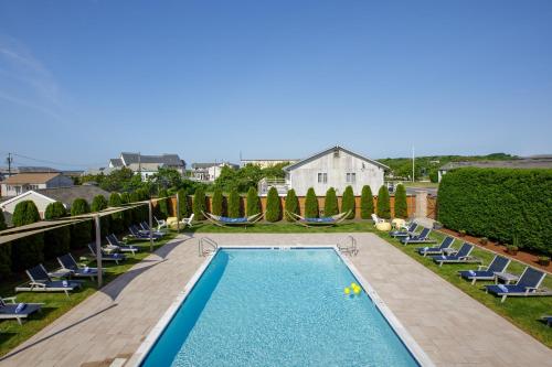 a swimming pool with lounge chairs and a house at Aqualina Inn Montauk in Montauk