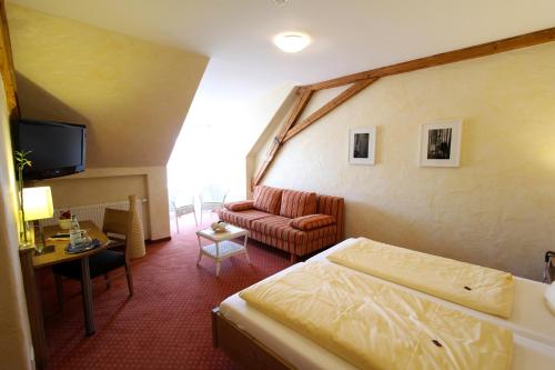 a hotel room with a bed and a couch at Weinhotel / Gasthaus zur Sonne in Ihringen
