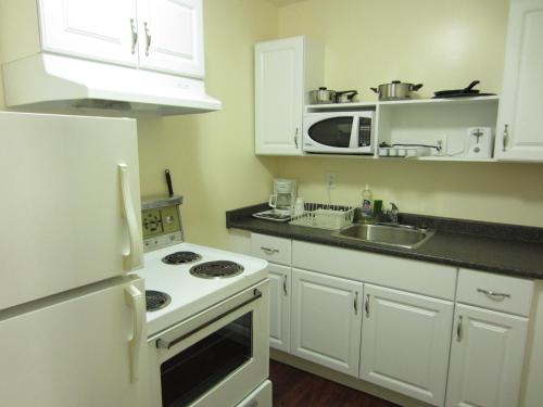 a kitchen with white appliances and a white refrigerator at Village Inn & Suites - Sudbury in Lively