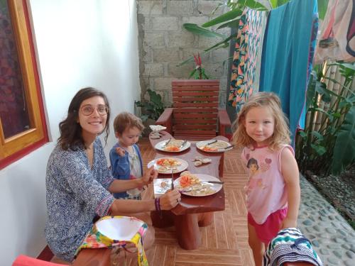 une femme et deux enfants assis à une table avec de la nourriture dans l'établissement Riung Guesthouse, à Riung