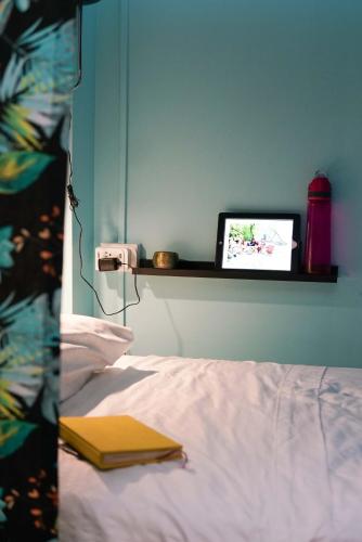 a bedroom with a bed with a laptop on a shelf at NATIVUS Art-Hostel in San José