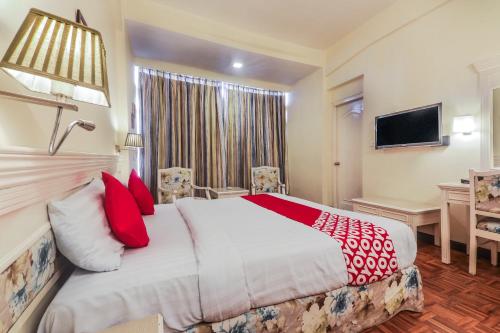 a hotel room with a large bed with red pillows at Alpine Continental in Shillong