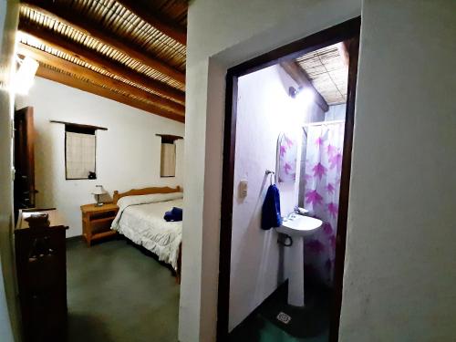 a bedroom with a bed and a bathroom with a sink at El Sol Hostel de Humahuaca in Humahuaca