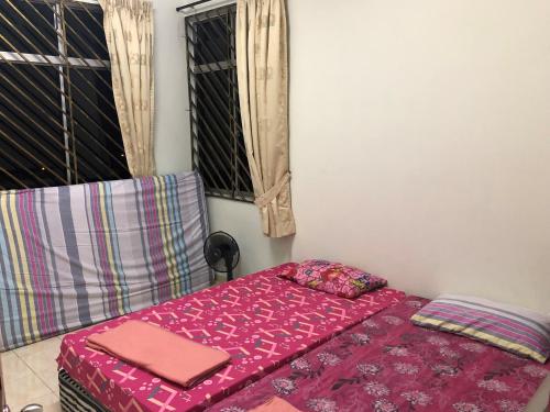 a bedroom with a bed with a pink bedspread at New Casa De Monte in Melaka