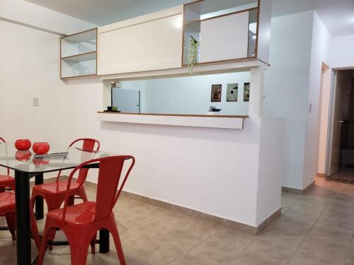 a dining room with a table and red chairs at Departamentos Temporarios Reggiardo in Resistencia